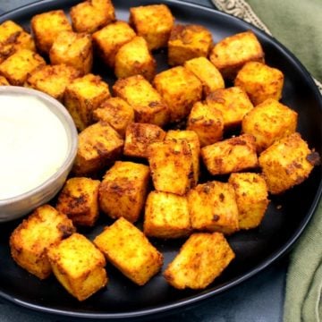 Photo of crispy air fryer tofu cubes baked in an air fryer with a bowl of vegan mayo