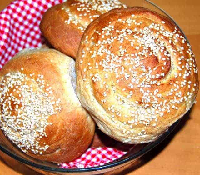 Garlic herb sandwich buns in basket with red and white checkered napkin.