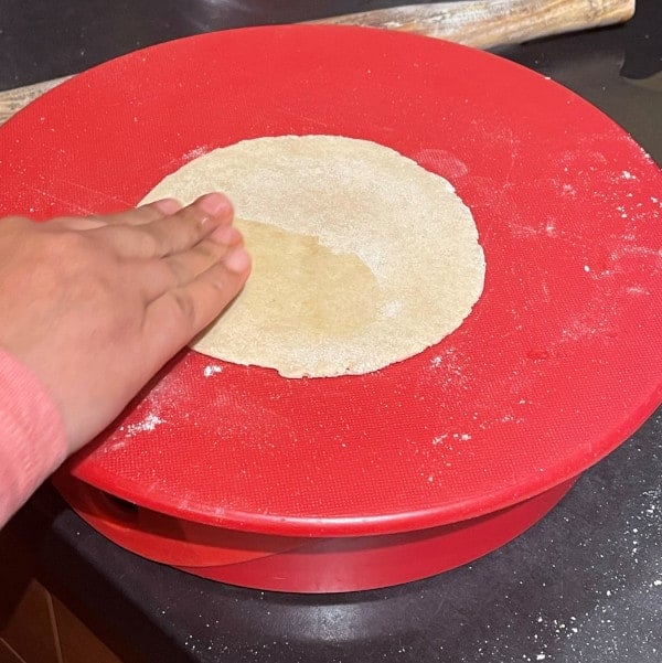 Sourdough discard roti being rolled and coated with oil.