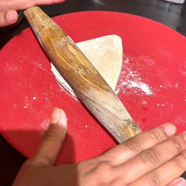 Photo of hands rolling a ghadichi poli or folded roti