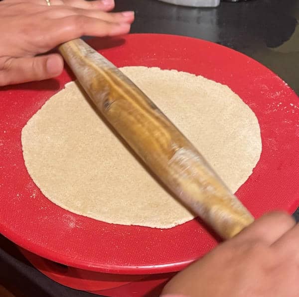 Sourdough roti being rolled with rolling pin.