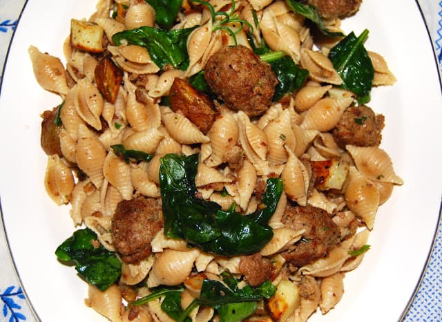 Vegan shell pasta with meatballs and spinach on plate.