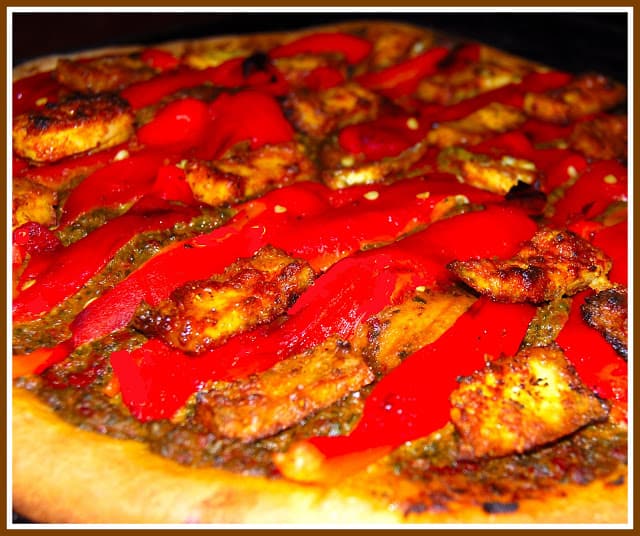 Photo of vegan tandoori tofu pizza with red bell pepper strips