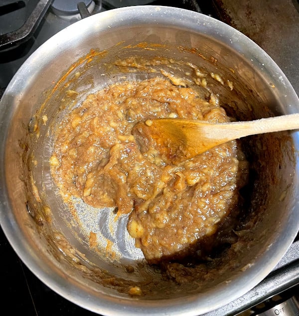 Banana jam in saucepan with wooden spoon.