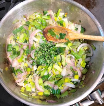 Leeks and scallions sauteeing in skillet with onions and garlic