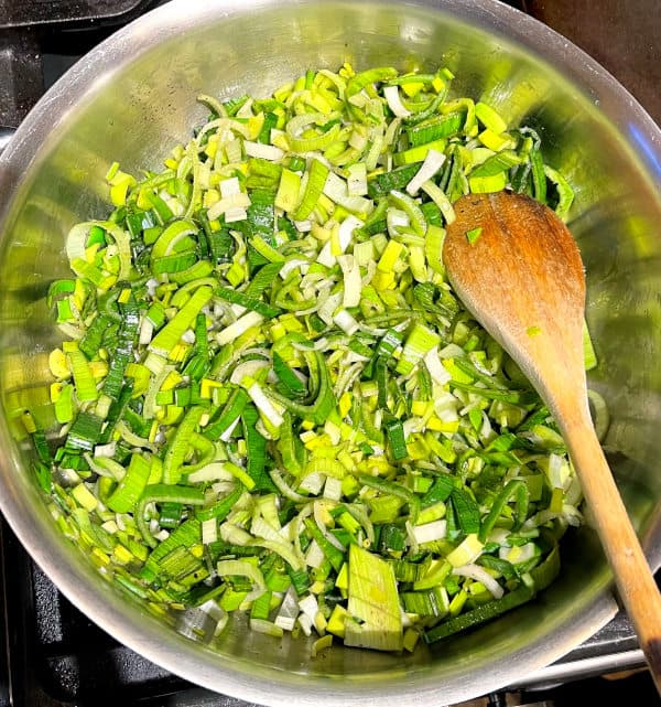 Leeks and other greens sauteing in pan for enchilada filling