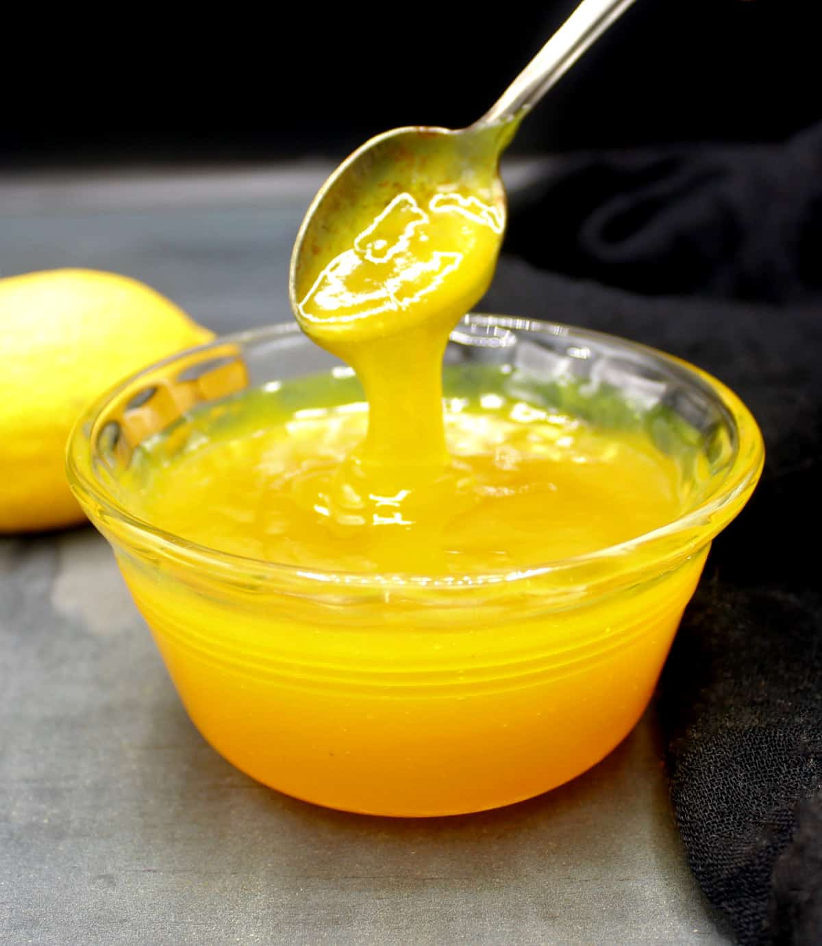 Vegan lemon curd being poured into bowl with spoon.