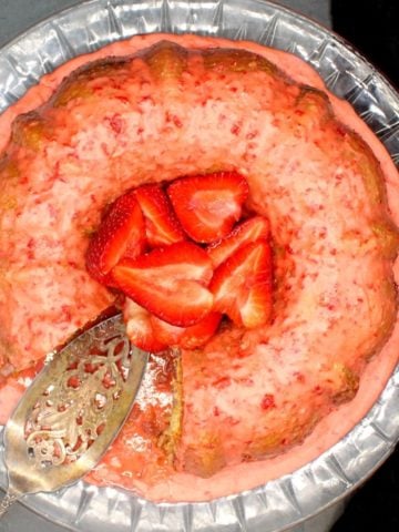 Overhead shot of vegan strawberry cake with fresh strawberries and a pink strawberry glaze