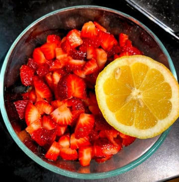 Strawberries and lemon in glass bowl