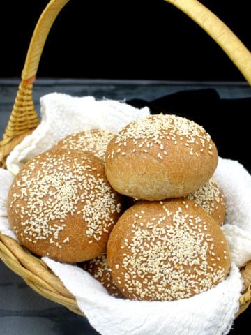 Homemade whole wheat burger buns nestled in a bread basket.