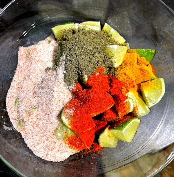 masala spices for lime pickle in bowl with quartered limes