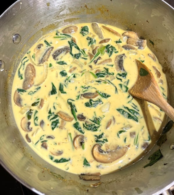 Spinach mushroom curry cooking in skillet.
