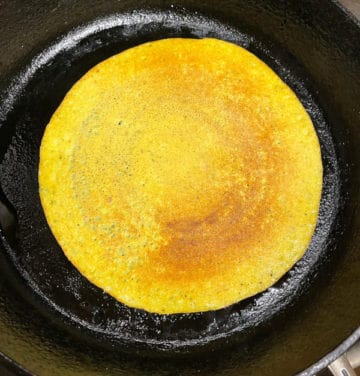 Adai dosa cooking on a griddle