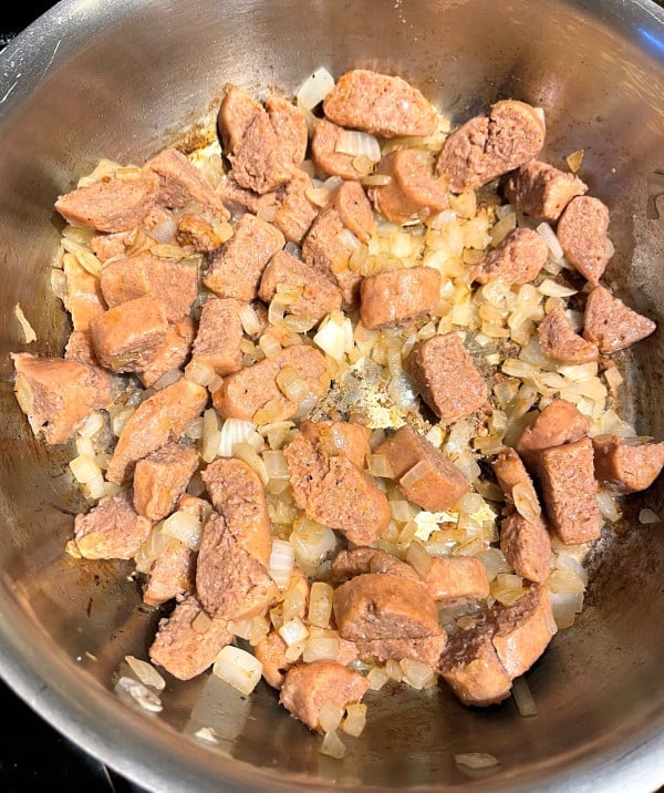 Vegan sausage browning with onions in skillet for feijoada