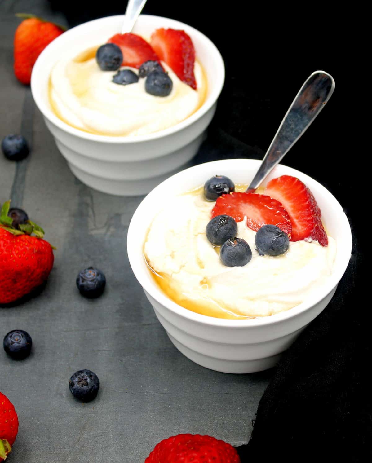 Photo of two white ramekins with vegan yogurt made in the Instant Pot and served with berries and a drizzle of maple syrup.
