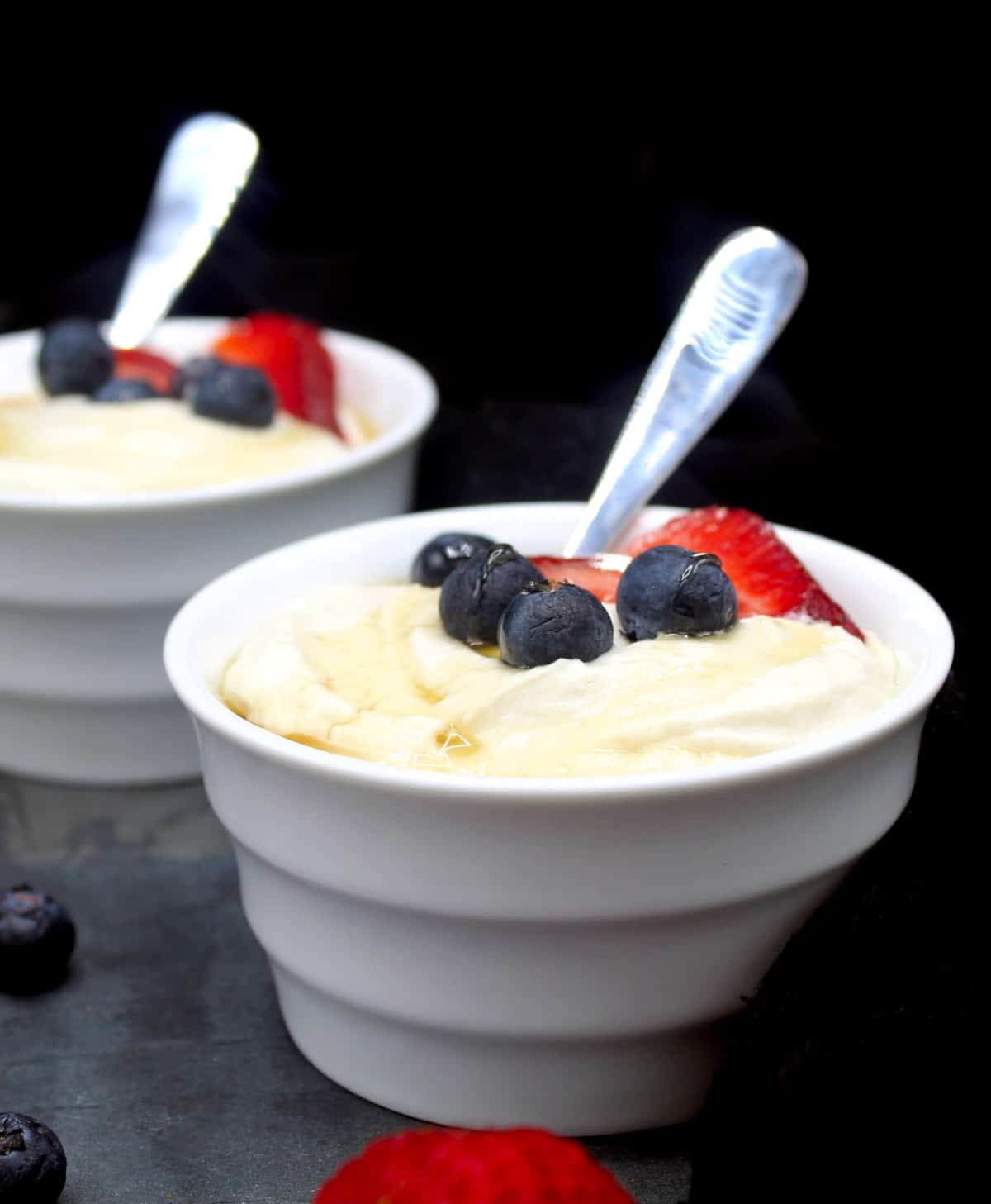 Bowls of vegan yogurt topped with strawberries and blueberries.