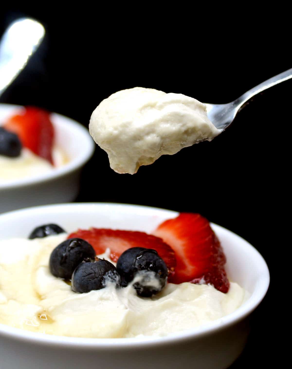 Photo of a thick spoonful of vegan Greek yogurt made in the Instant Pot and served with strawberries, blueberries and maple syrup.