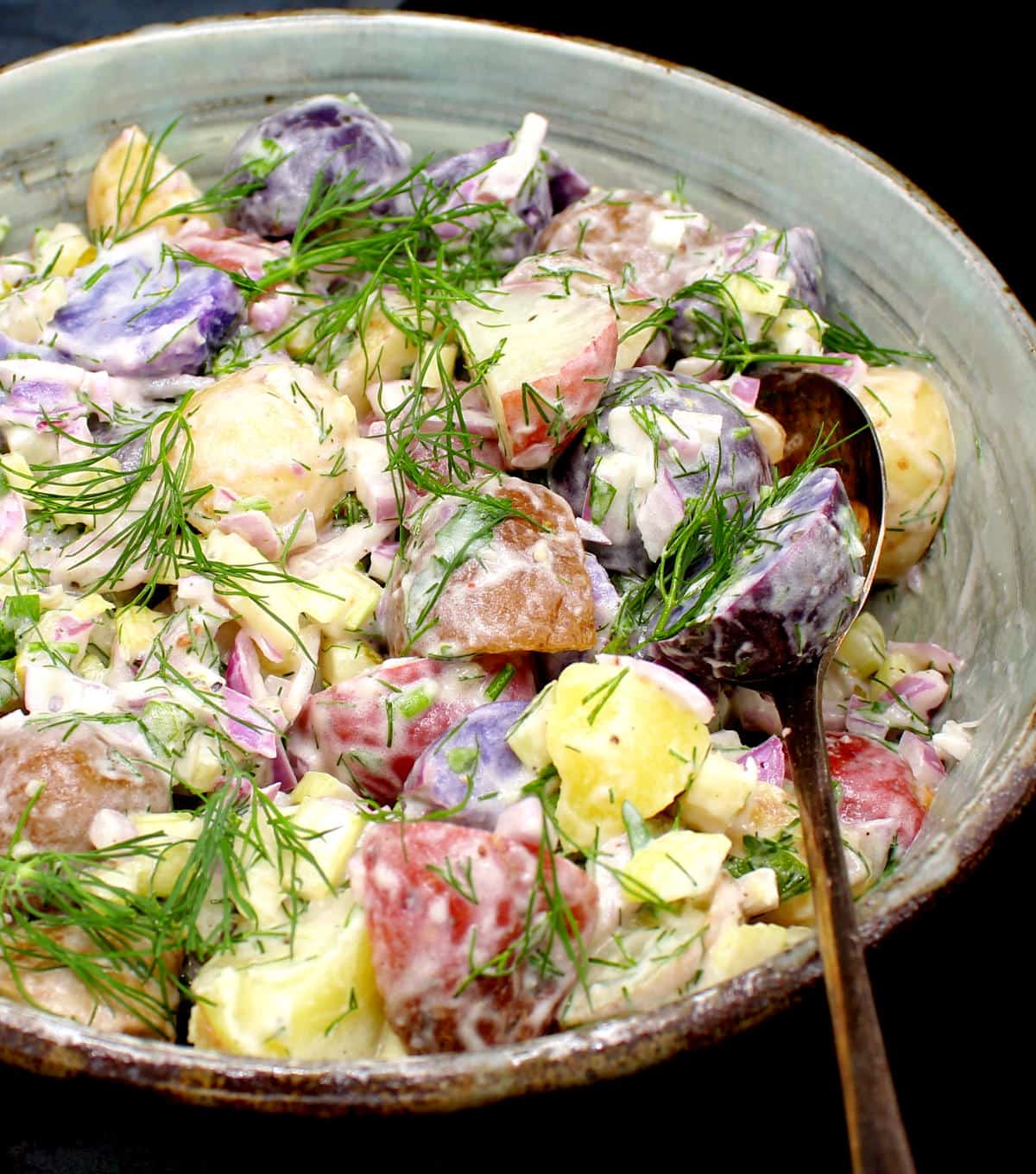 Closeup photo of vegan potato salad in a bowl with a spoon.