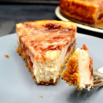 A slice of vegan strawberry rhubarb cheesecake with a morsel on a fork to show the creamy filling.