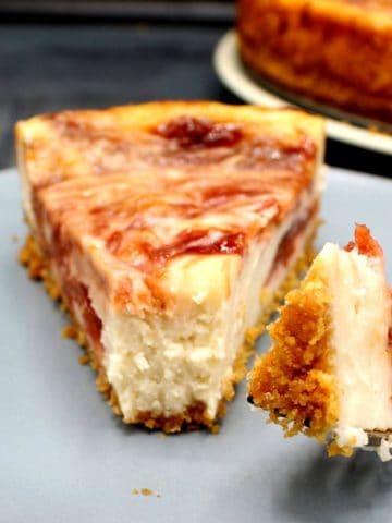A slice of vegan strawberry rhubarb cheesecake with a morsel on a fork to show the creamy filling.