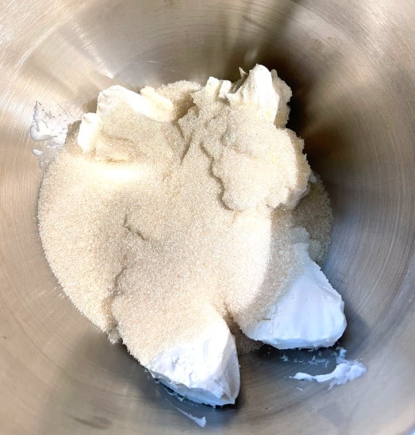 Vegan cream cheese, sugar and other ingredients in stand mixer bowl.