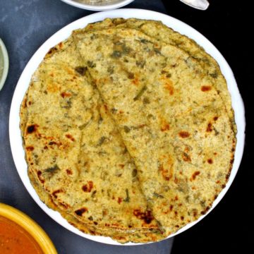Photo of palak paratha stacked on a white plate