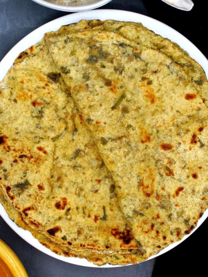 Photo of palak paratha stacked on a white plate