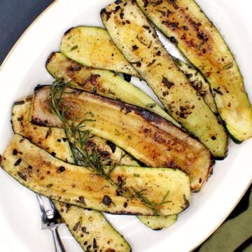 Pan roasted zucchini slices arranged in a white platter