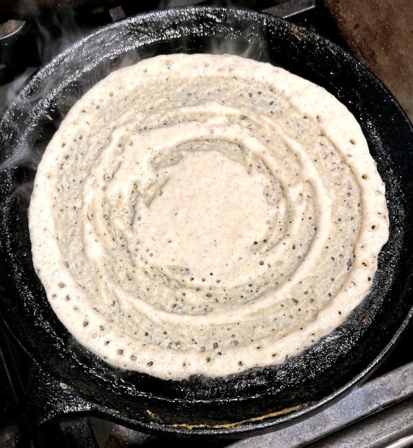 Sorghum dosa cooking on cast iron griddle
