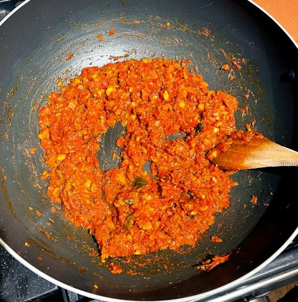 Tomatoes reducing in wok with onions and spices for tomato chutney.