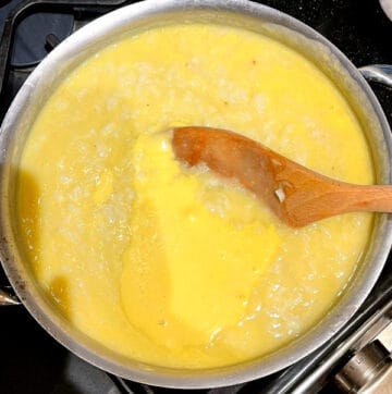 Photo of vegan mango congee cooking in pot with wooden spoon