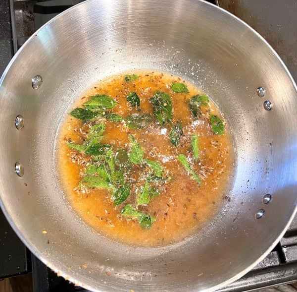 Tamarind sauce and curry leaves cooking with spices in saucepan