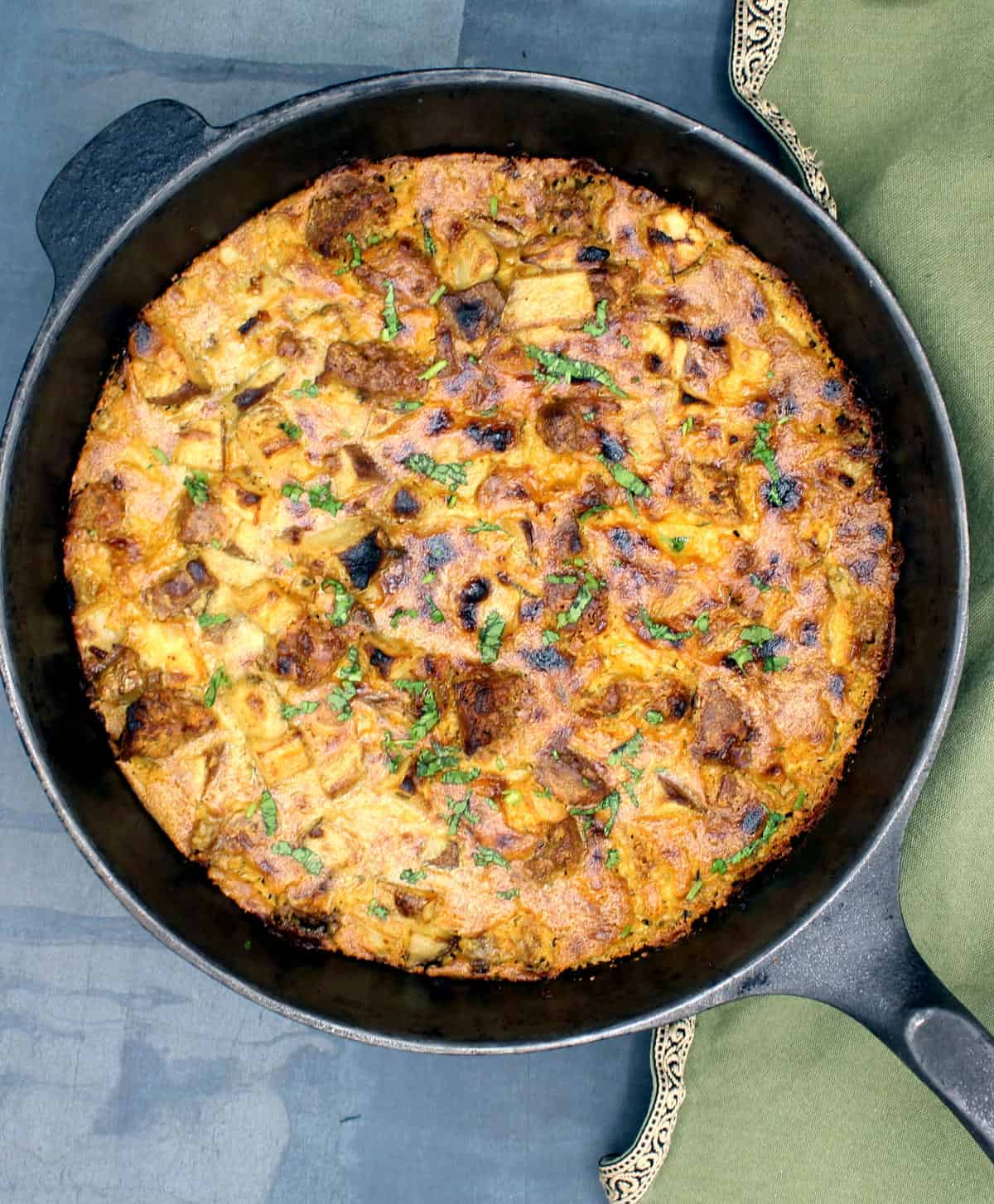 Cheesy vegan breakfast potato casserole in cast iron pan.