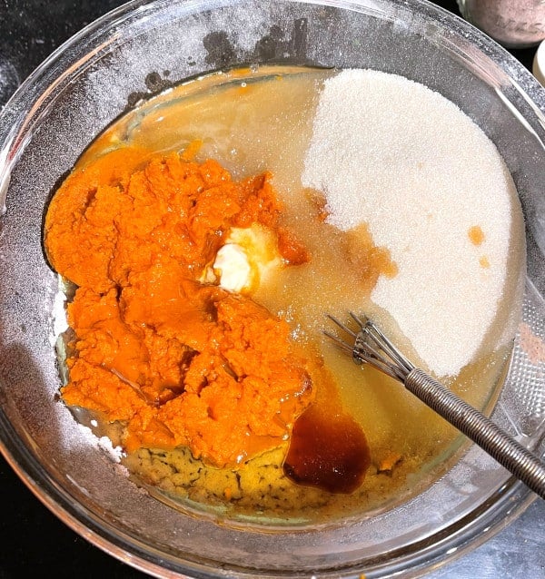 pumpkin cake ingredients in bowl with whisk