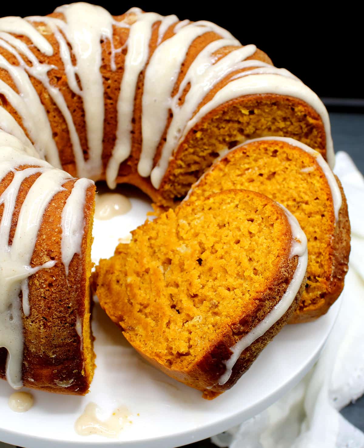 Front photo of slices of cake cut out of a vegan pumpkin bundt cake with glaze.