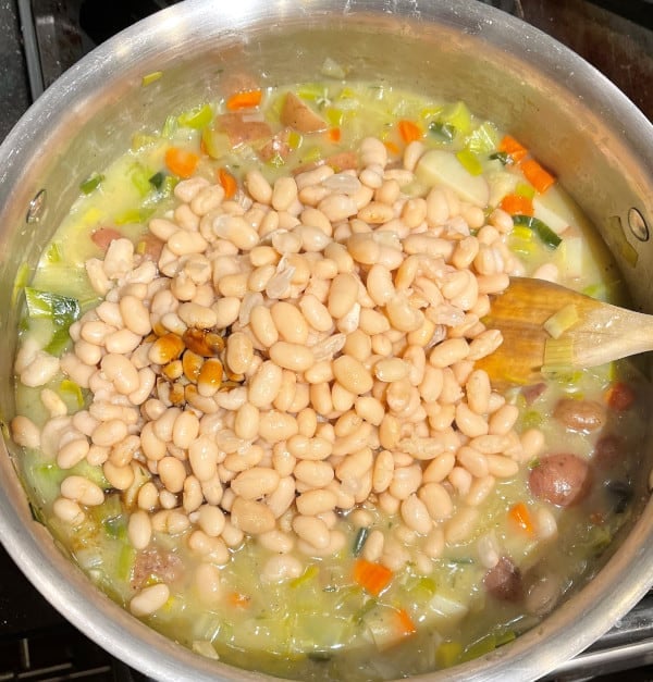 Beans, worcestershire and liquid aminos added to veggies in saucepan