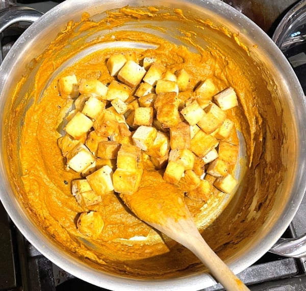 Tofu cubes added to saucepan with curry paste