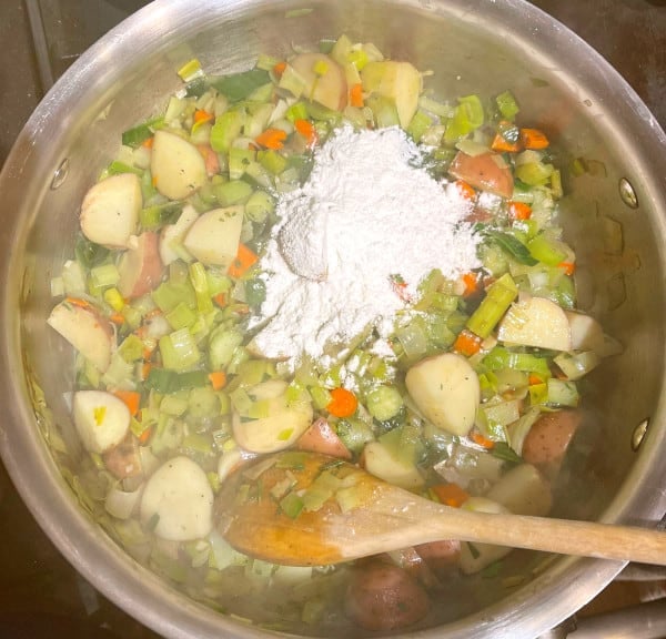 Carrots, potatoes and celery cooking in pot with flour added.
