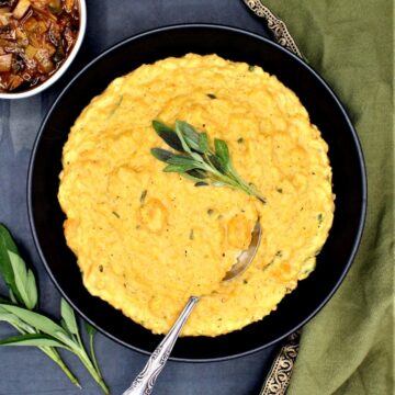 A black bowl with vegan butternut squash risotto with sage leaves and mushroom stew