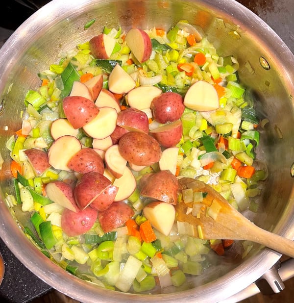 Potatoes added to carrots, leeks and celery in saucepan