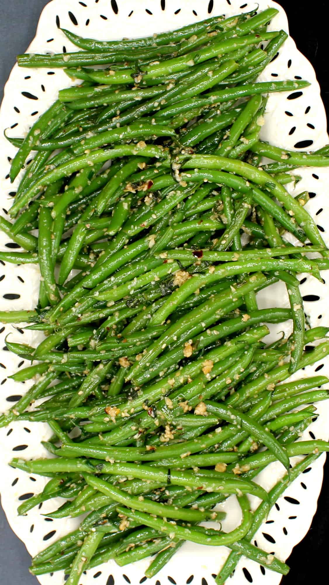 Overhead photo of garlic green beans with sesame and red pepper flakes on a white platter.