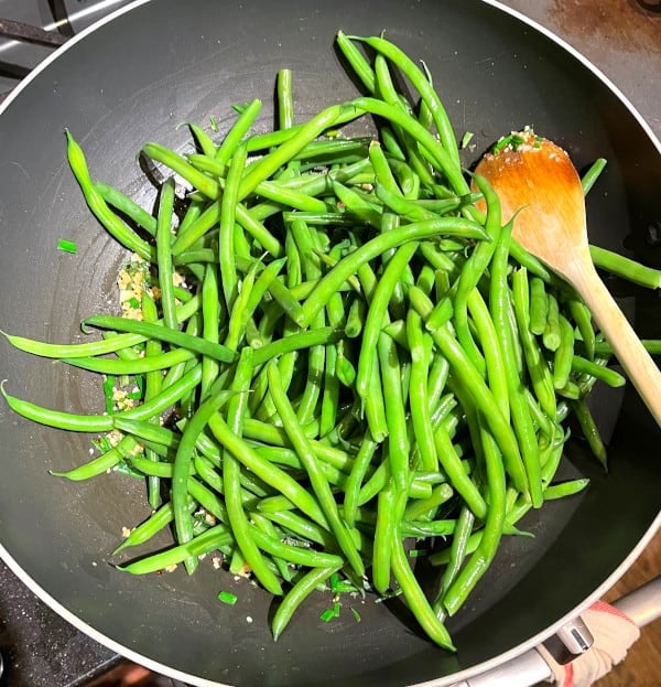 green beans added to wok with garlic and herbs.