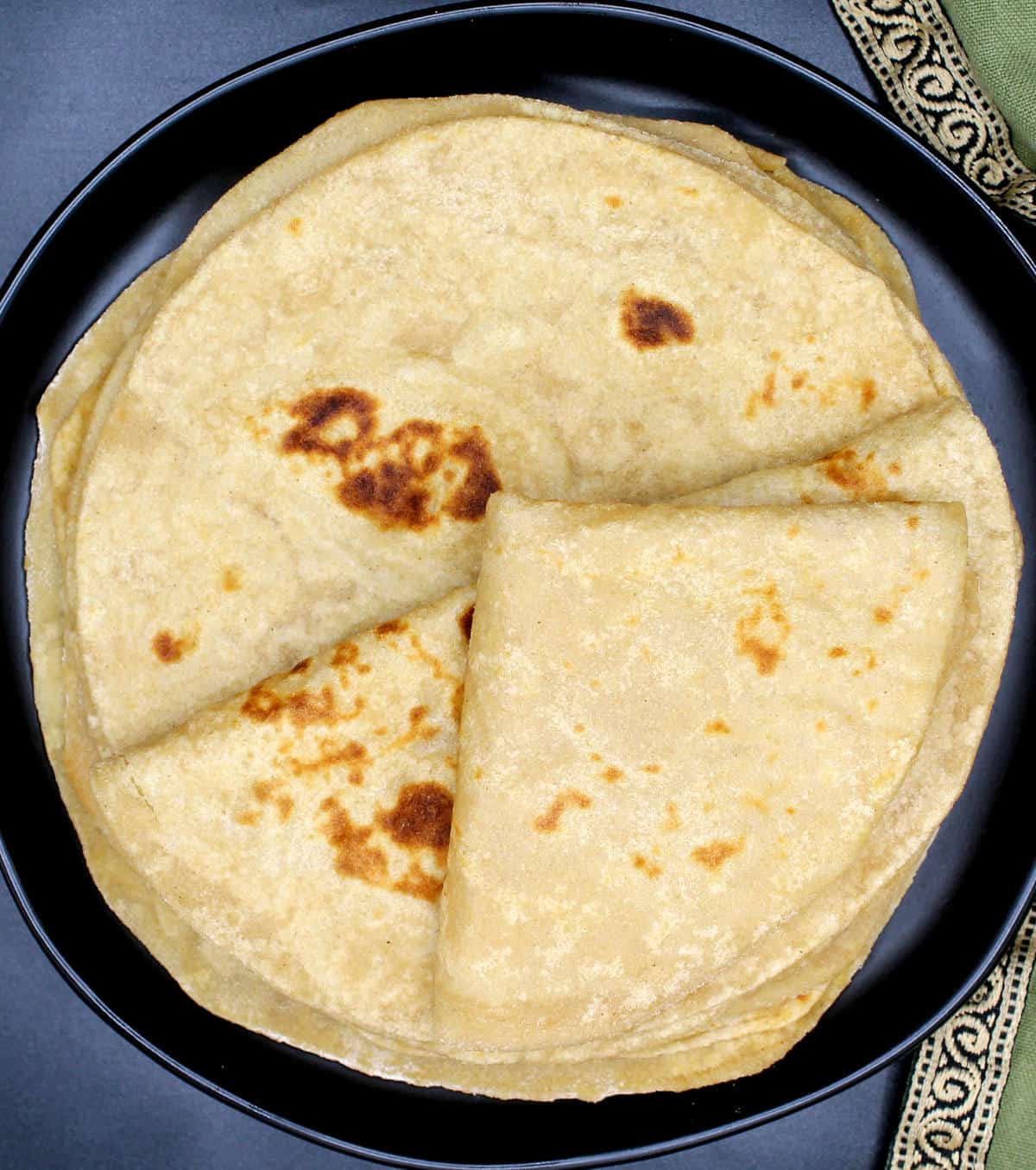 Overhead photo showing rotis folded and stacked on a black plate.