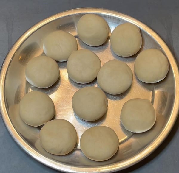 12 balls of roti dough in steel plate.