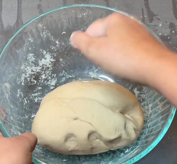 Kneading roti dough in bowl.