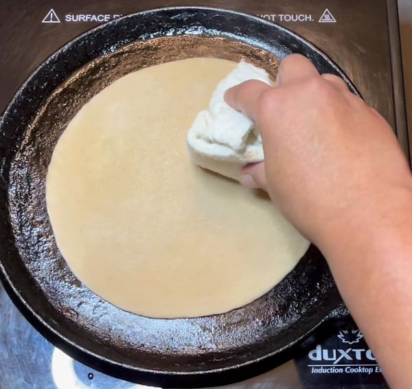 Pressing down on edges of roti while cooking