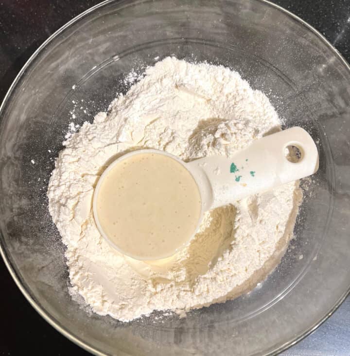 Glass bowl with all purpose flour and sourdough in a cup
