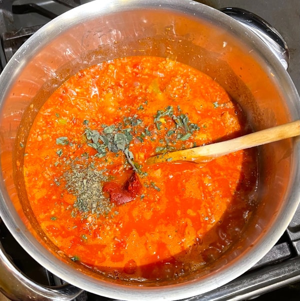 Herbs and tomato paste added to tomato sauce and veggies