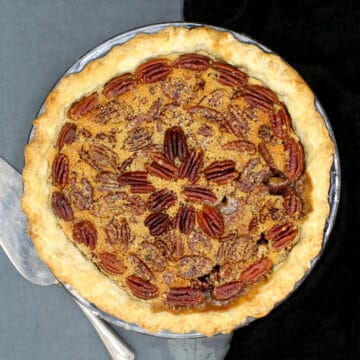 Image of a perfectly baked vegan pecan pie with a pie server next to it.