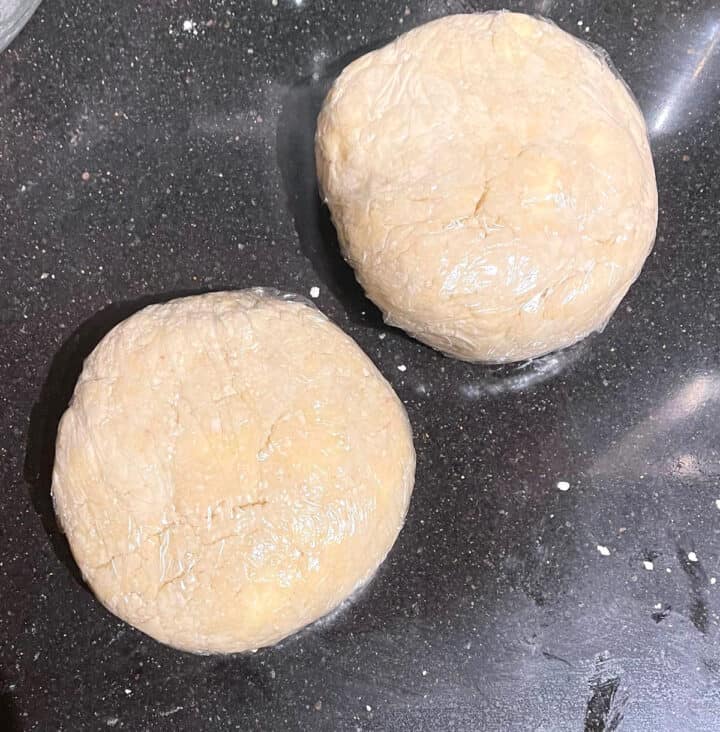 Two rounds of vegan sourdough pie crust in cling wrap.